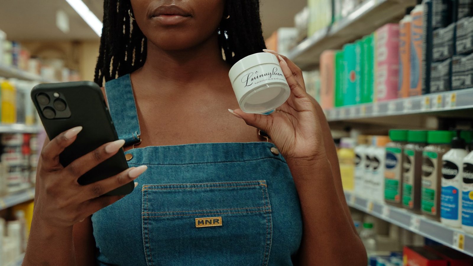 Woman using a cosmetic ingredient scanner app on moisturizer in a pharmacy aisle