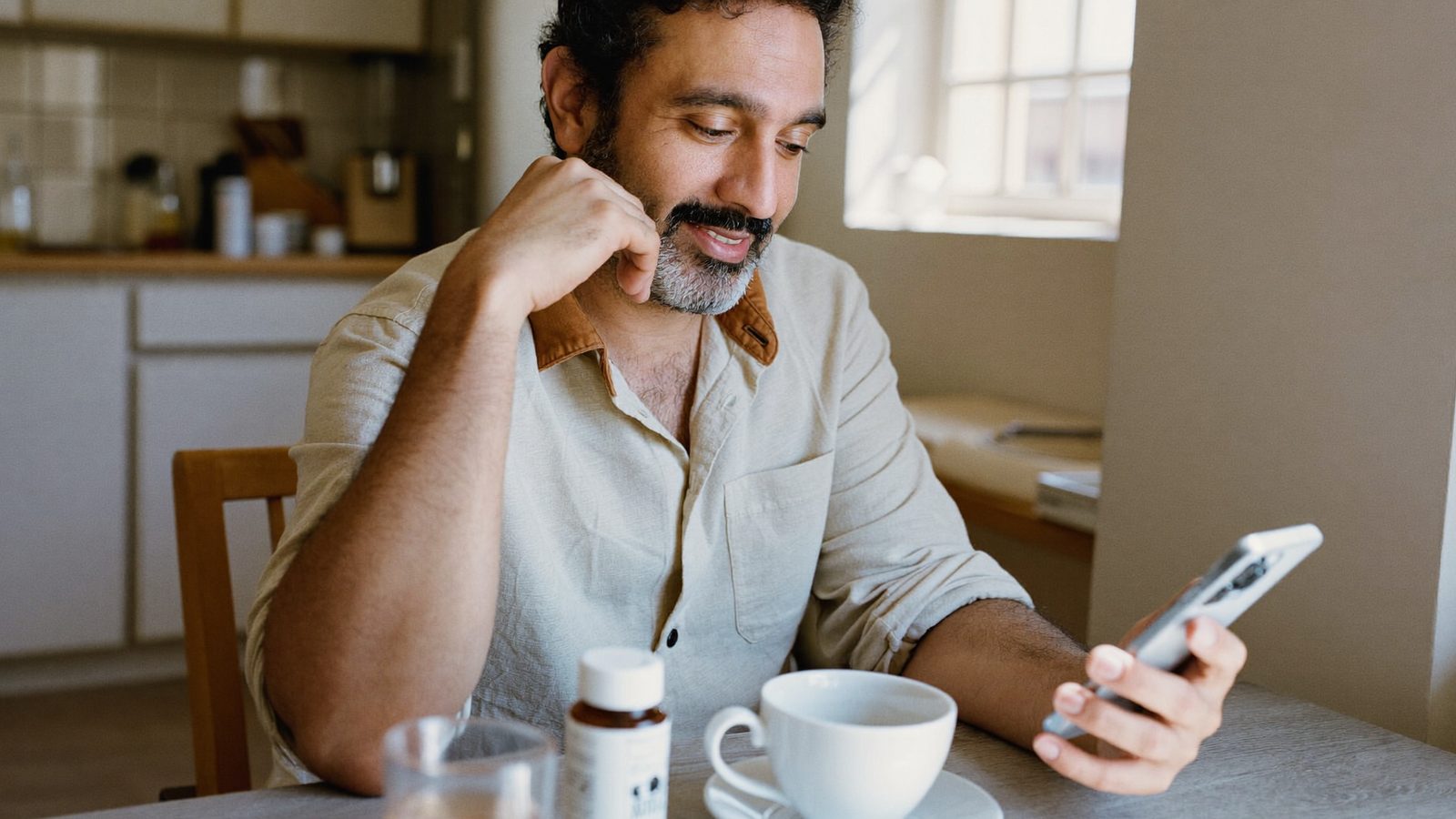 Man reviewing a supplement score on his phone at his kitchen table