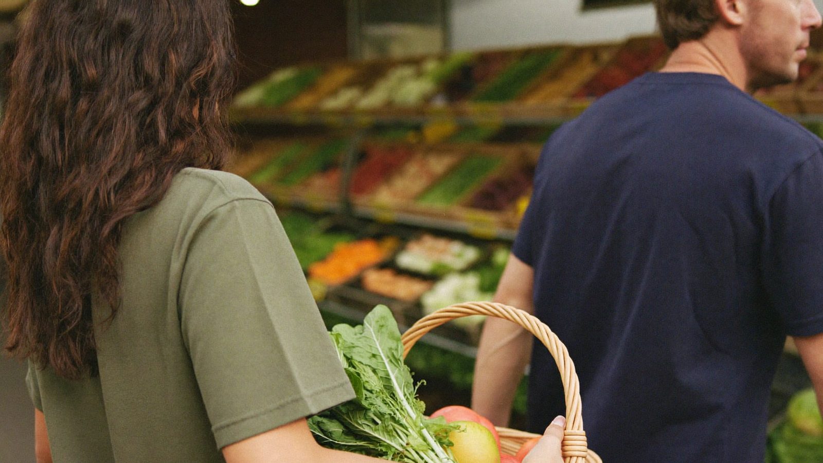 Two shoppers choosing fresh produce side by side while testing scanner apps